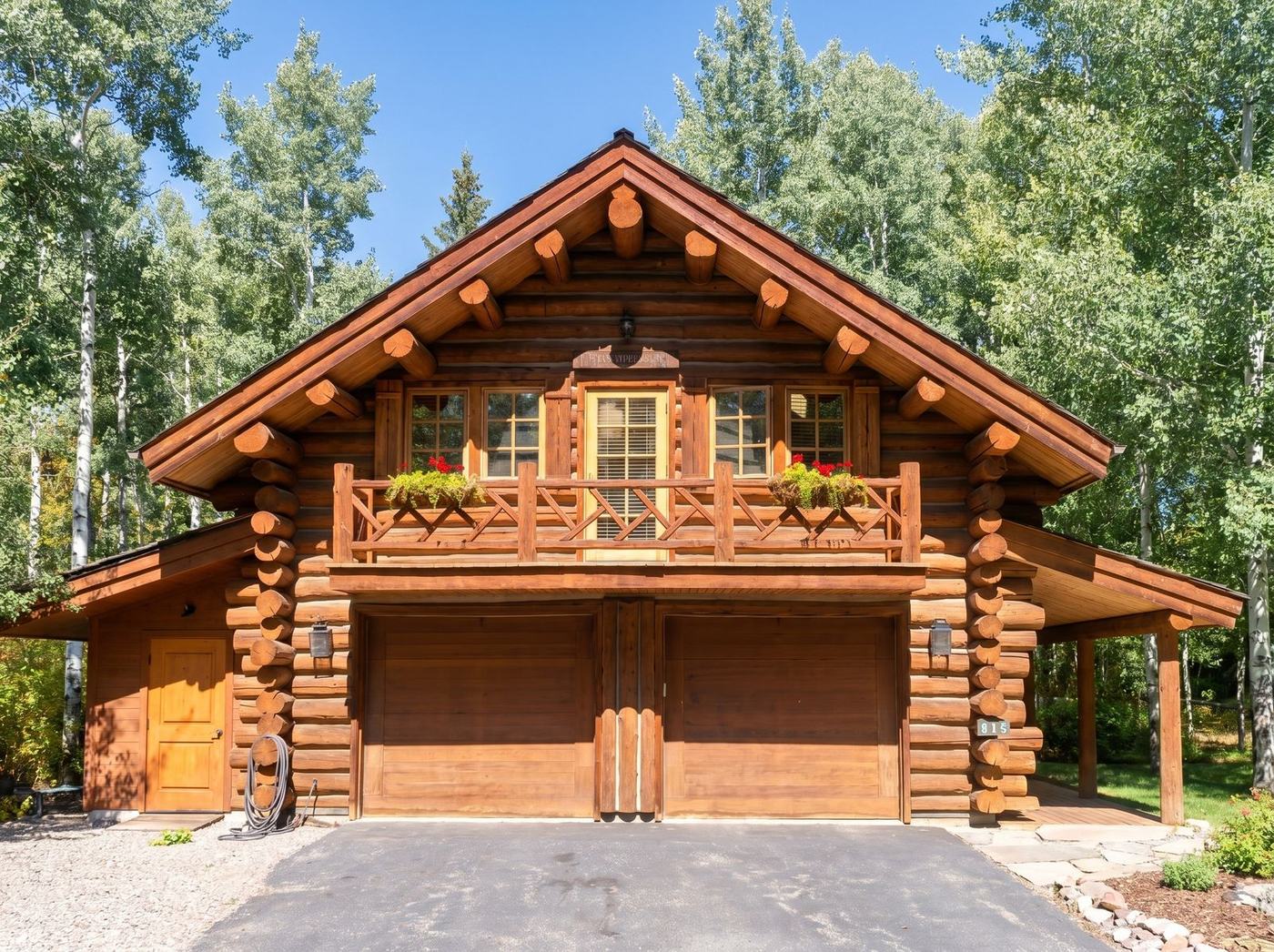 Custom log home in a Sun Valley aspen grove — steep gable, balcony, and two-bay garage